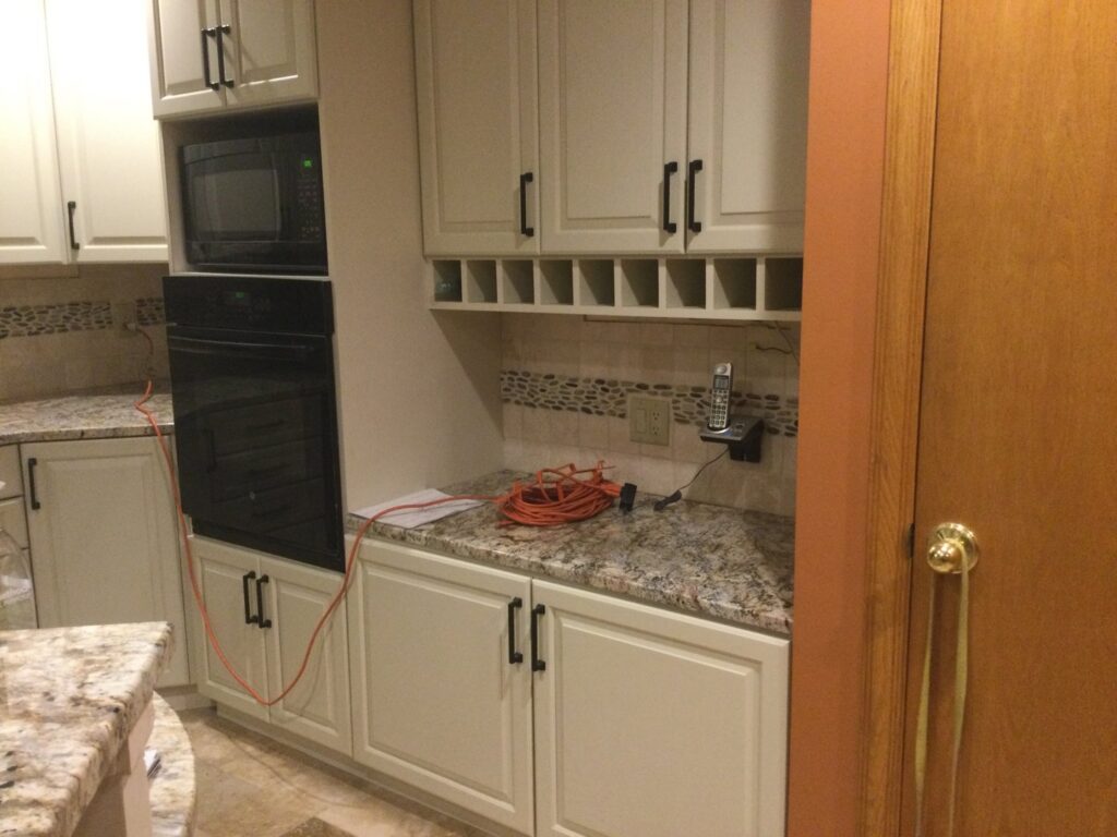 A kitchen with newly installed light cabinets and granite countertops, showing work in progress by Cincinnati Cabinet Refacing in Cincinnati, OH.