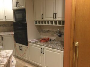 A kitchen with newly installed light cabinets and granite countertops, showing work in progress by Cincinnati Cabinet Refacing in Cincinnati, OH.