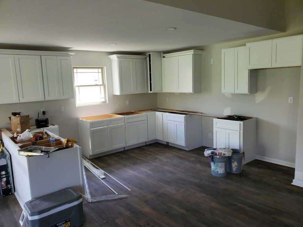 Kitchen cabinet installation in progress with white cabinets installed and tools on the floor by GCI Services, Inc. in Simpsonville, SC
