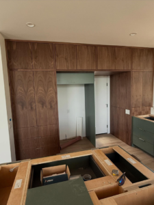 A kitchen under construction with custom wooden upper and green base cabinets being installed by Red Beard Cabinets in Kansas City, MO.