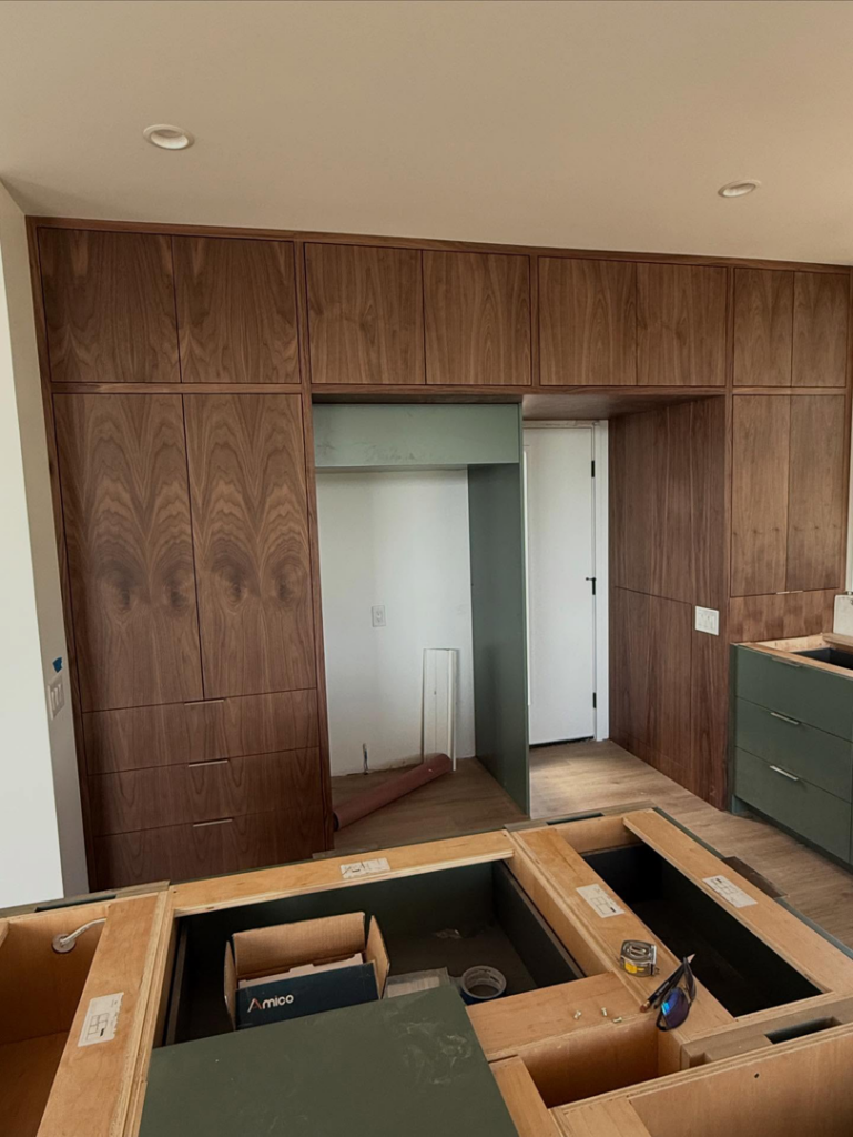A kitchen under construction with custom wooden upper and green base cabinets being installed by Red Beard Cabinets in Kansas City, MO.