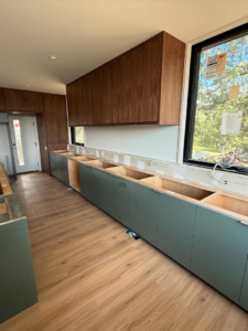 A long view of a kitchen under construction with upper and lower cabinets installed by Red Beard Cabinets in Kansas City, MO.