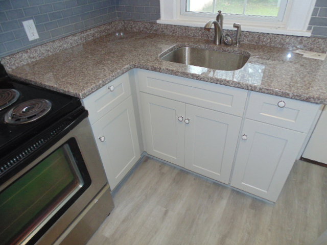New white kitchen cabinets with granite countertops and a stainless steel sink installed by Pro Renovations Savannah, GA.