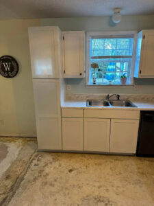 New white kitchen cabinets installed over a prepared subfloor during a renovation by Bryder Construction in Greenville, SC.
