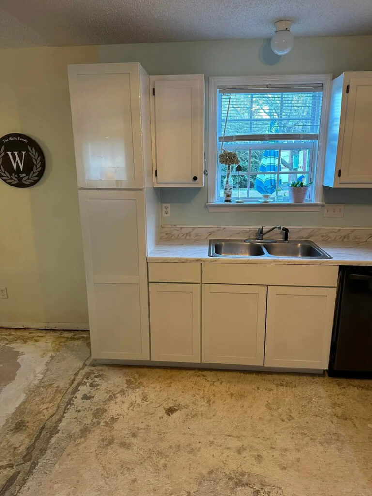 New white kitchen cabinets installed over a prepared subfloor during a renovation by Bryder Construction in Greenville, SC.