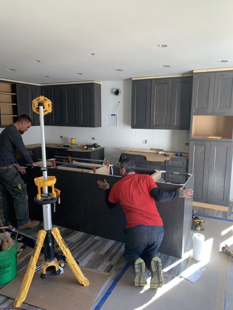 Workers installing kitchen cabinets and an island for Waldron Construction, Kitchen & Bath in Antioch, IL