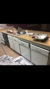 Kitchen cabinets being painted white with drawers removed, showing a painting project by Mancusi Home Maintenance in Boulder City, NV.