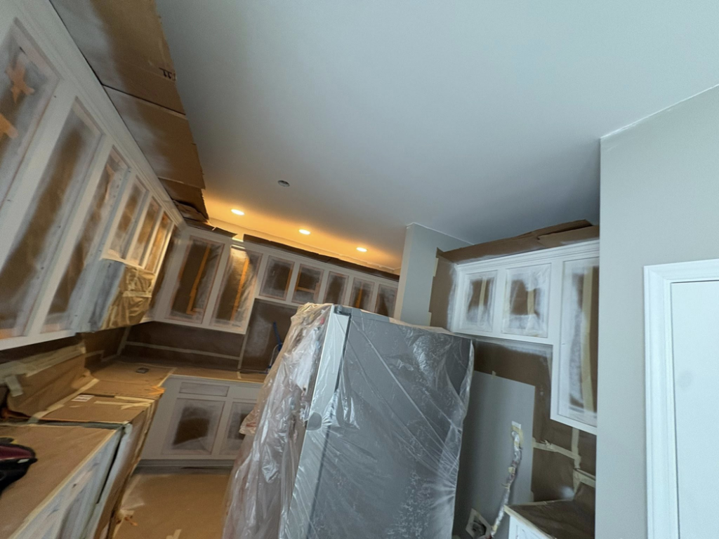 Kitchen cabinets taped and covered for painting during a home improvement project by Mauricio's Home Improvements in Raleigh, NC.
