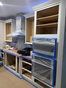 Kitchen cabinets taped and prepped for painting during a renovation project by Coastal Surface Design in Virginia Beach, VA.