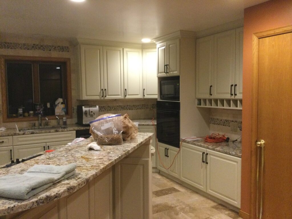 A kitchen showcasing light-colored refaced cabinets, granite countertops, and built-in appliances by Cincinnati Cabinet Refacing in Cincinnati, OH.