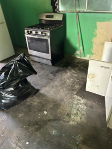 A kitchen undergoing cleanout with a stove, black trash bags, and old cabinet doors, handled by Discount Hauling in Las Cruces, NM.