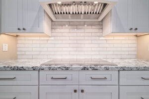 Close-up of a kitchen cooktop, subway tile backsplash, and range hood installed by Ignite Construction in Tempe, AZ.