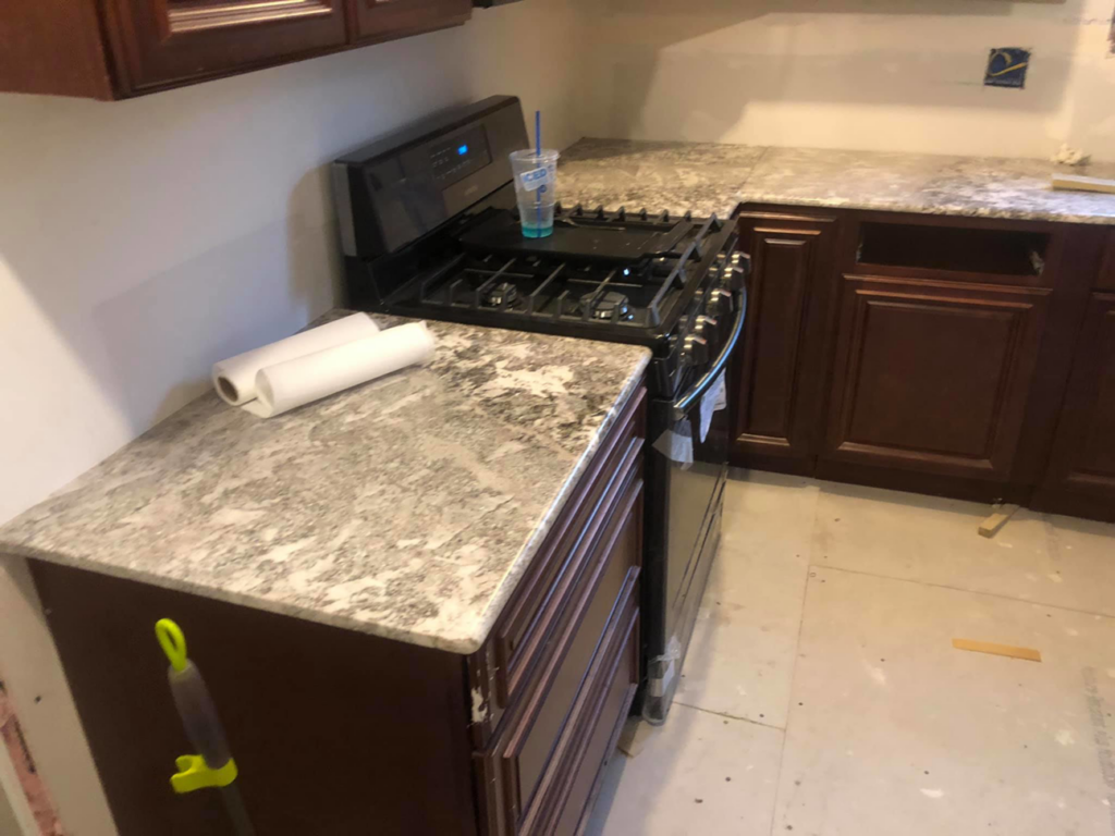 A corner section of a newly installed granite countertop next to a stove by Fine Design Marble And Granite in Springfield, MA.