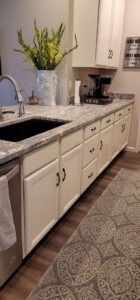 A close-up of a newly installed kitchen counter and white cabinets with a sink by LJ Builders in Chandler, AZ