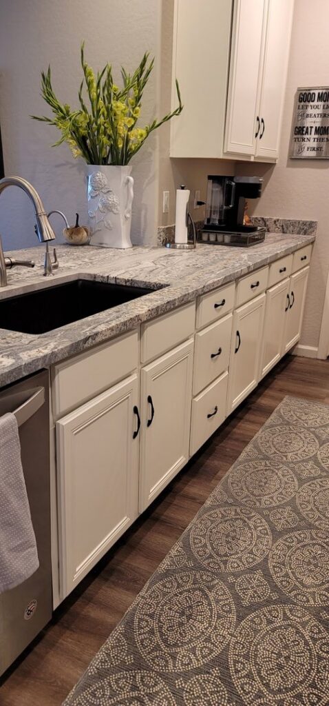 A close-up of a newly installed kitchen counter and white cabinets with a sink by LJ Builders in Chandler, AZ