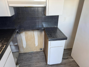 A kitchen area with black tiled countertop and exposed wall, showing the 'before' state of a resurfacing project by That Resurfacing Guy LLC in Oklahoma City, OK.