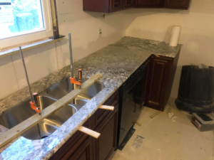 Kitchen countertop installation process showing new granite being secured with clamps by Fine Design Marble And Granite in Springfield, MA.