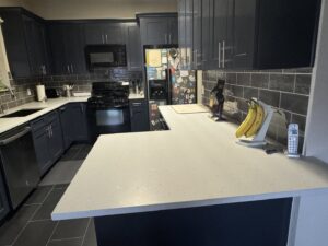 A kitchen remodel featuring dark cabinets, light countertops, and a subway tile backsplash by AAA Countertops in Austin, TX.