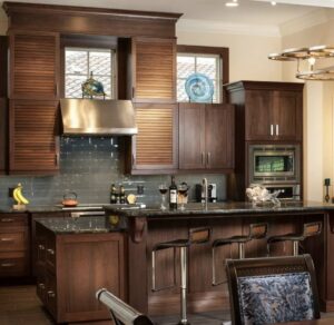 A kitchen remodel featuring dark wood cabinets, louvered doors, and a large island by Kornerstone Kitchens in Orlando, FL.