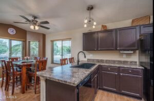 A renovated kitchen and dining area with dark brown cabinets and countertops by Desert Remodel in Scottsdale, AZ.