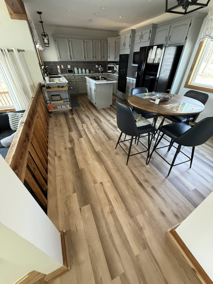 A modern kitchen and dining area featuring new flooring and a wooden railing installed by M Squared Construction LLC in Tonganoxie, KS.