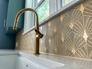 A close-up of a new gold kitchen faucet and patterned backsplash installed by Kore Construction LLC in Cincinnati, OH.