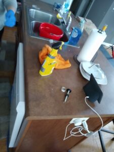 A kitchen counter with a small part and cleaning supplies, suggesting a faucet repair in progress by Lincoln Household Services in Lincoln, NE.