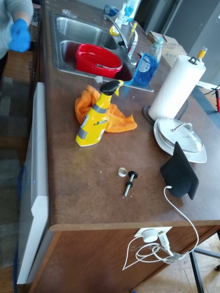 A kitchen counter with a small part and cleaning supplies, suggesting a faucet repair in progress by Lincoln Household Services in Lincoln, NE.