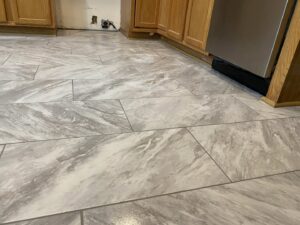 A newly installed grey marble-look tile floor in a kitchen by Goubar Tile And More in Raleigh, NC.
