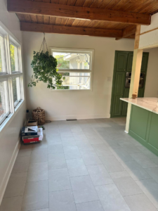 Newly installed grey floor tiles and green cabinets in a renovated kitchen by Bryder Construction in Greenville, SC.