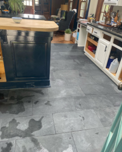 Newly installed dark grey rectangular floor tiles in a kitchen by Infinite Construction LLC in Bristol, CT.