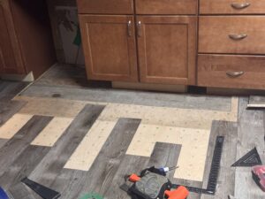 Kitchen flooring installation in progress with tools visible, performed by Hawk Handyman Services in West Fargo, ND