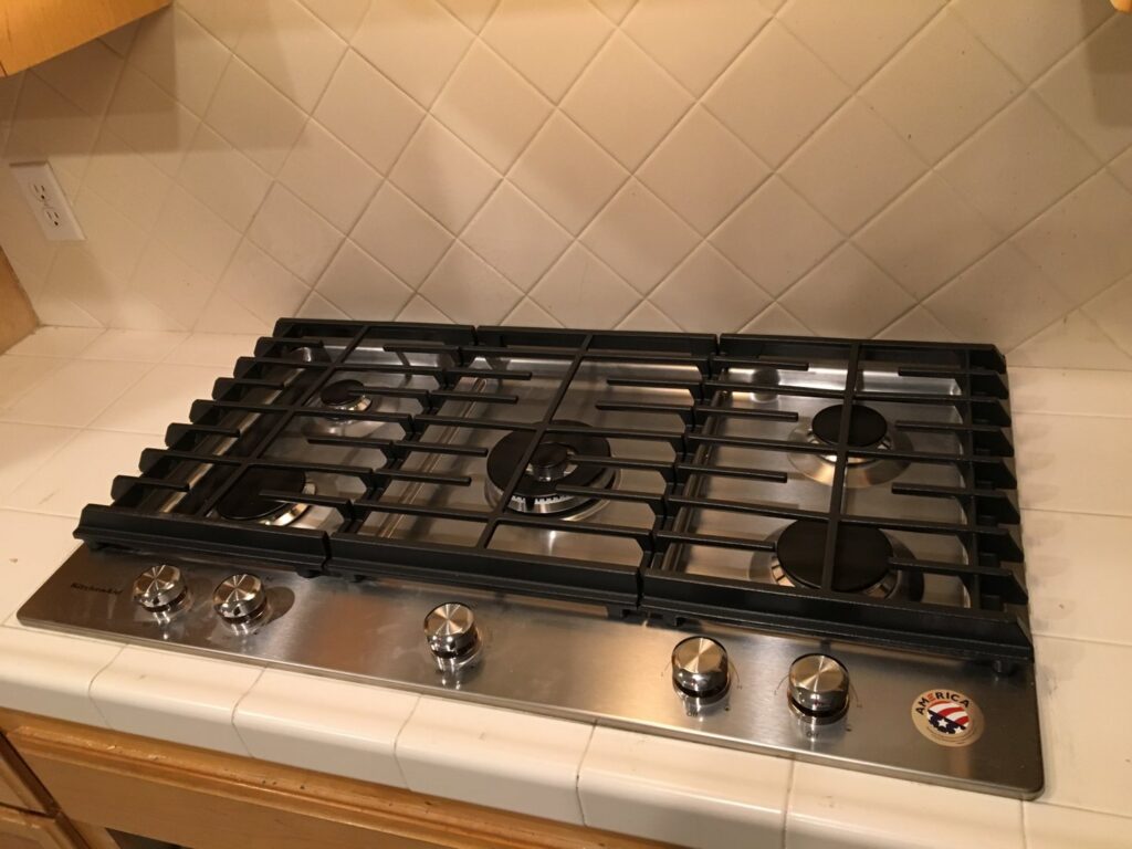 A newly installed stainless steel gas cooktop in a kitchen by Red Gator Maintenance in Fresno, CA.