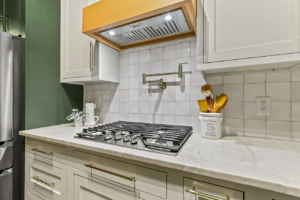 A modern kitchen gas range with a white tile backsplash and green accent wall by Innovative Design & Construction in Linwood, KS.