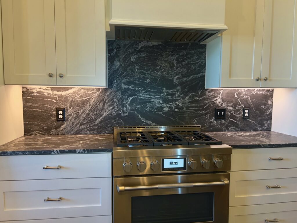 A kitchen stovetop area with a dark, patterned granite backsplash and countertop installed by Counter Fitters in Savannah, GA