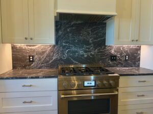A kitchen stovetop area with a dark, patterned granite backsplash and countertop installed by Counter Fitters in Savannah, GA