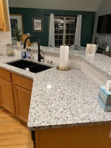 A modern kitchen with newly installed granite countertops and a white tile backsplash by Affordable Granite of KC in Kansas City, MO.