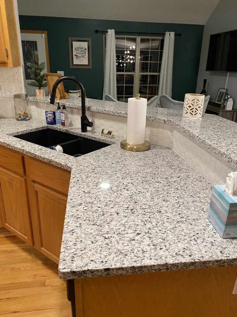 A modern kitchen with newly installed granite countertops and a white tile backsplash by Affordable Granite of KC in Kansas City, MO.