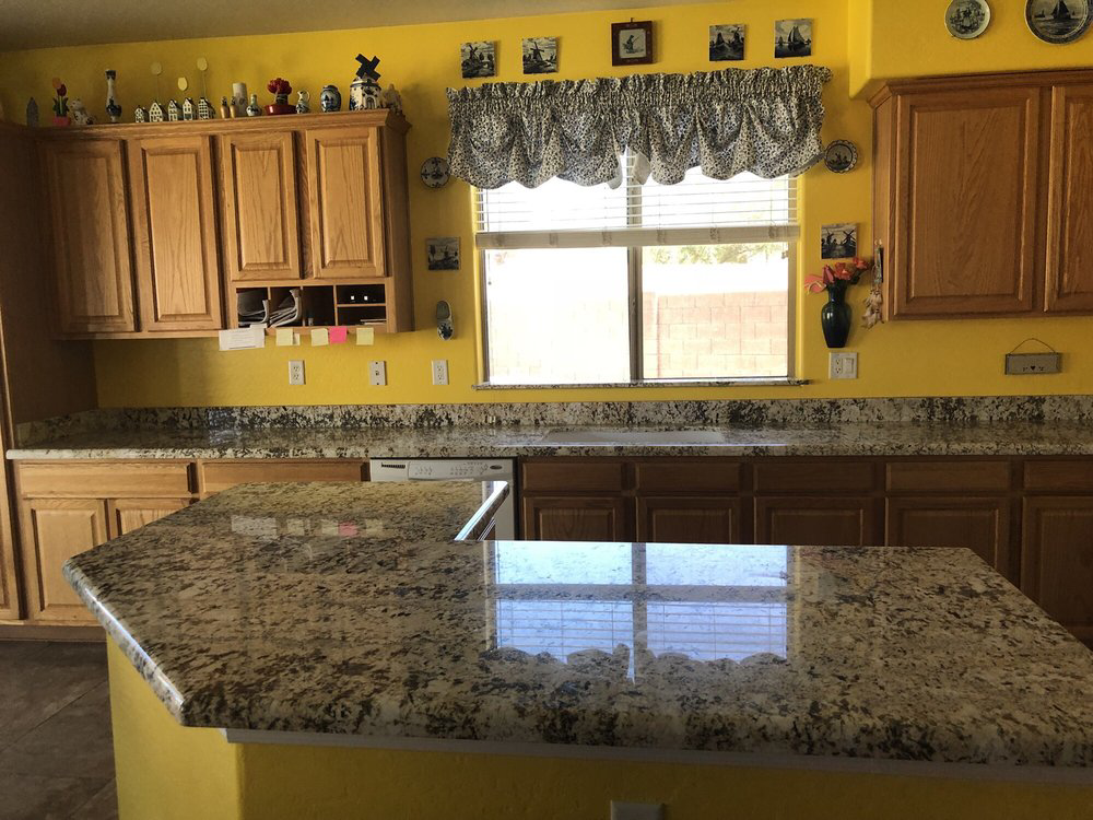A kitchen featuring granite countertops and wooden cabinets with yellow walls by L&M Granite Countertops in Phoenix, AZ.