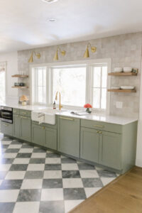 A kitchen remodel with green cabinets, white countertops, and a distinctive black and white checkered floor by AAA Countertops in Austin, TX.