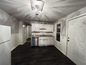 A newly painted kitchen interior with white cabinets and dark flooring by The First Choice Painting in San Antonio, TX