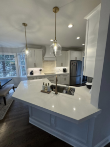 A modern kitchen island with a sink and stylish pendant lights installed by Branch Home Improvement LLC in Raleigh, NC.
