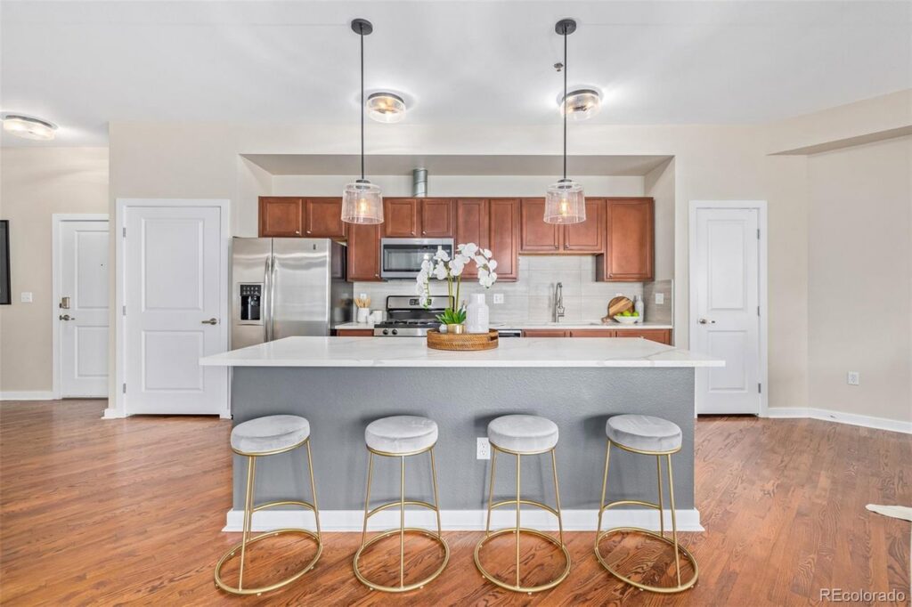 A modern kitchen featuring a large island with bar stools and stylish pendant lights, renovated by RAW Renovation in Denver, CO.