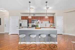 A modern kitchen featuring a large island with bar stools and stylish pendant lights, renovated by RAW Renovation in Denver, CO.