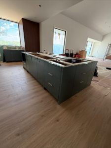 A large green kitchen island frame and base cabinets being installed by Red Beard Cabinets in Kansas City, MO.