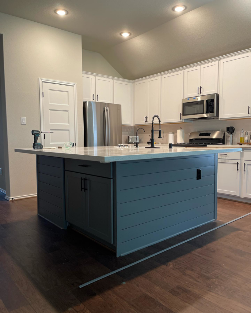 A modern kitchen featuring a newly installed island, white cabinets, and stainless steel appliances, a project by M7 Remodel & Restoration Inc. in Houston, TX
