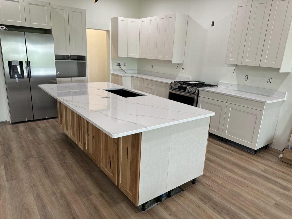 A kitchen renovation in progress with new white cabinets and a large island with quartz countertop by Northeast SD Handyman in Watertown, SD.