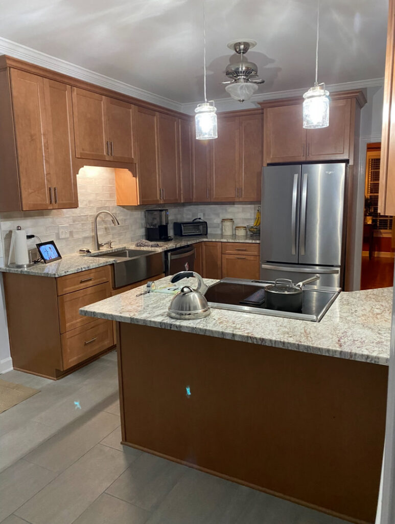 Kitchen with wooden cabinets and an island featuring a cooktop by Berco Construction LLC in Godfrey, IL