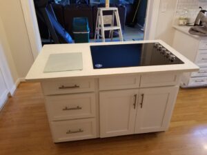 A kitchen island with a built-in induction cooktop and white cabinets installed by M J Services Home Remodeling in Gaithersburg, MD.