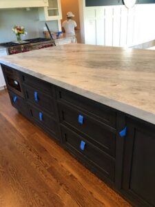 Newly installed kitchen island countertop with dark cabinets and blue tape by Centennial Granite in New Haven, CT.